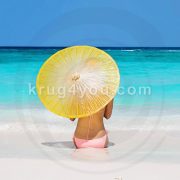 Девушка под зонтиком от солнца на пляже
